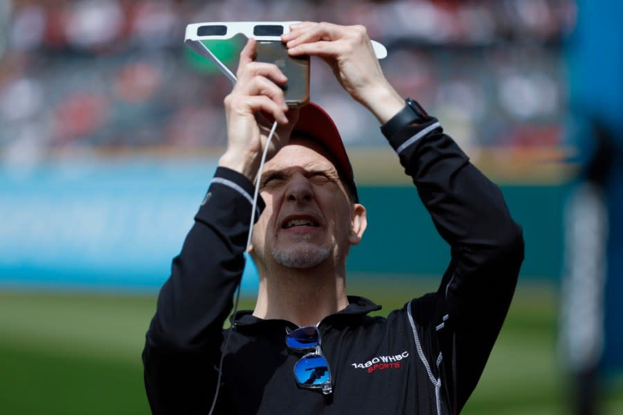 Kenny Roda uses special glasses to take a picture of the total solar eclipse, Monday, April 8, 2024, in Cleveland. (AP Photo/Ron Schwane)