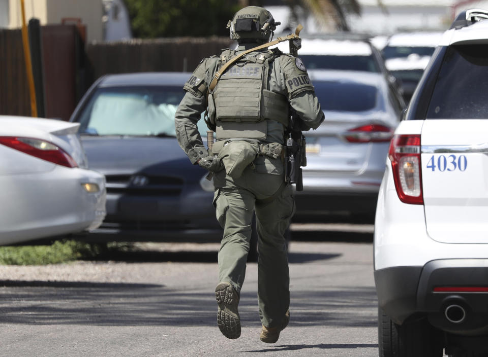 A Tucson Police SWAT officer runs down N. Palo Verde Ave. to a shooting scene at Lind Commons Apartments in Tucson, Ariz., on Thursday, Aug. 27, 2022. A local constable was among four people fatally shot at the apartment complex while serving an eviction notice. (Kelly Presnell/Arizona Daily Star via AP)