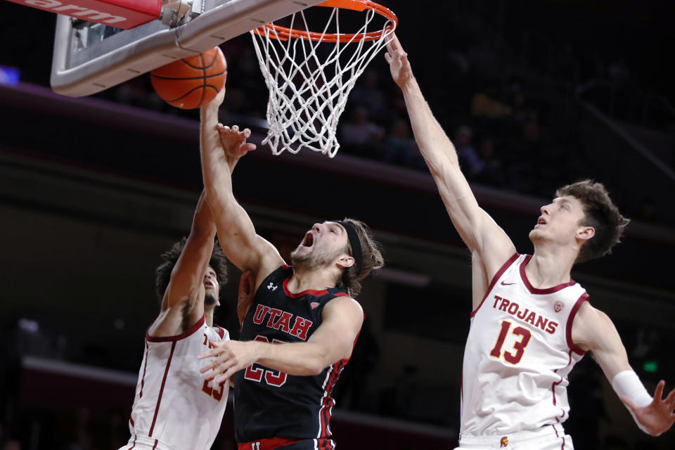 Southern California forward Max Agbonkpolo, left, blocks a shot by Utah guard Rollie Worster, center, with Southern California guard Drew Peterson, right, defending during the first half of an NCAA college basketball game in Los Angeles, Wednesday, Dec. 1, 2021. (AP Photo/Alex Gallardo)
