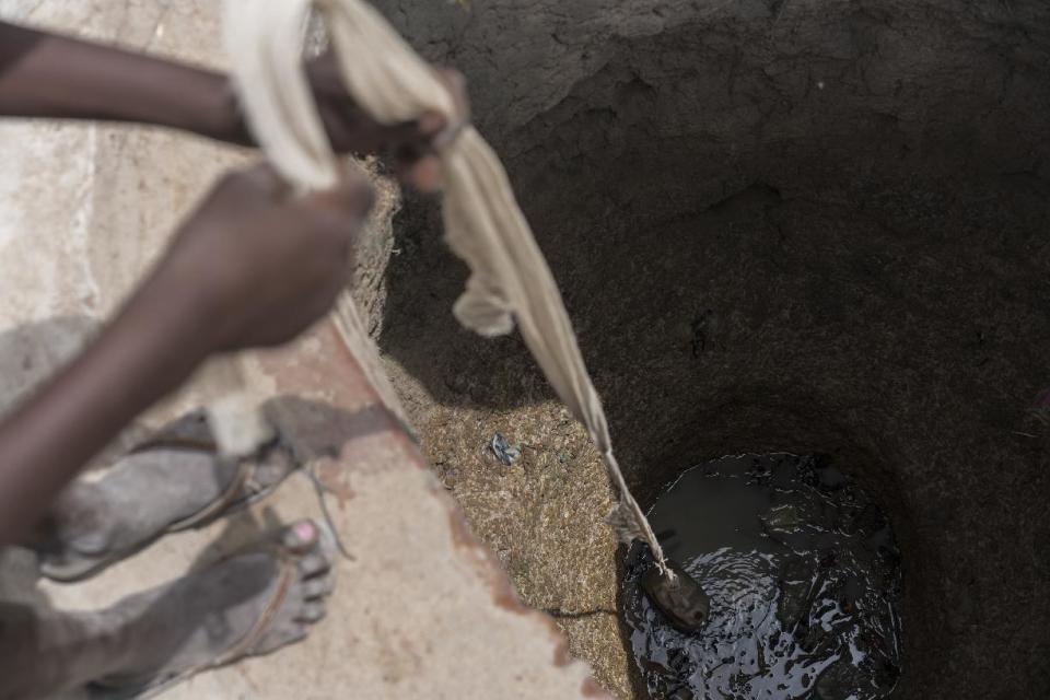 In this photo taken Sunday, March 12, 2017, a girl Abuk gathers dirty water from an old well in her village in Aweil, in South Sudan. As World Water Day approaches on March 22, more than 5 million people in South Sudan, do not have access to safe, clean water, compounding the problems of famine and civil war, according to the UNICEF. (Mackenzie Knowles-Coursin/UNICEF via AP)