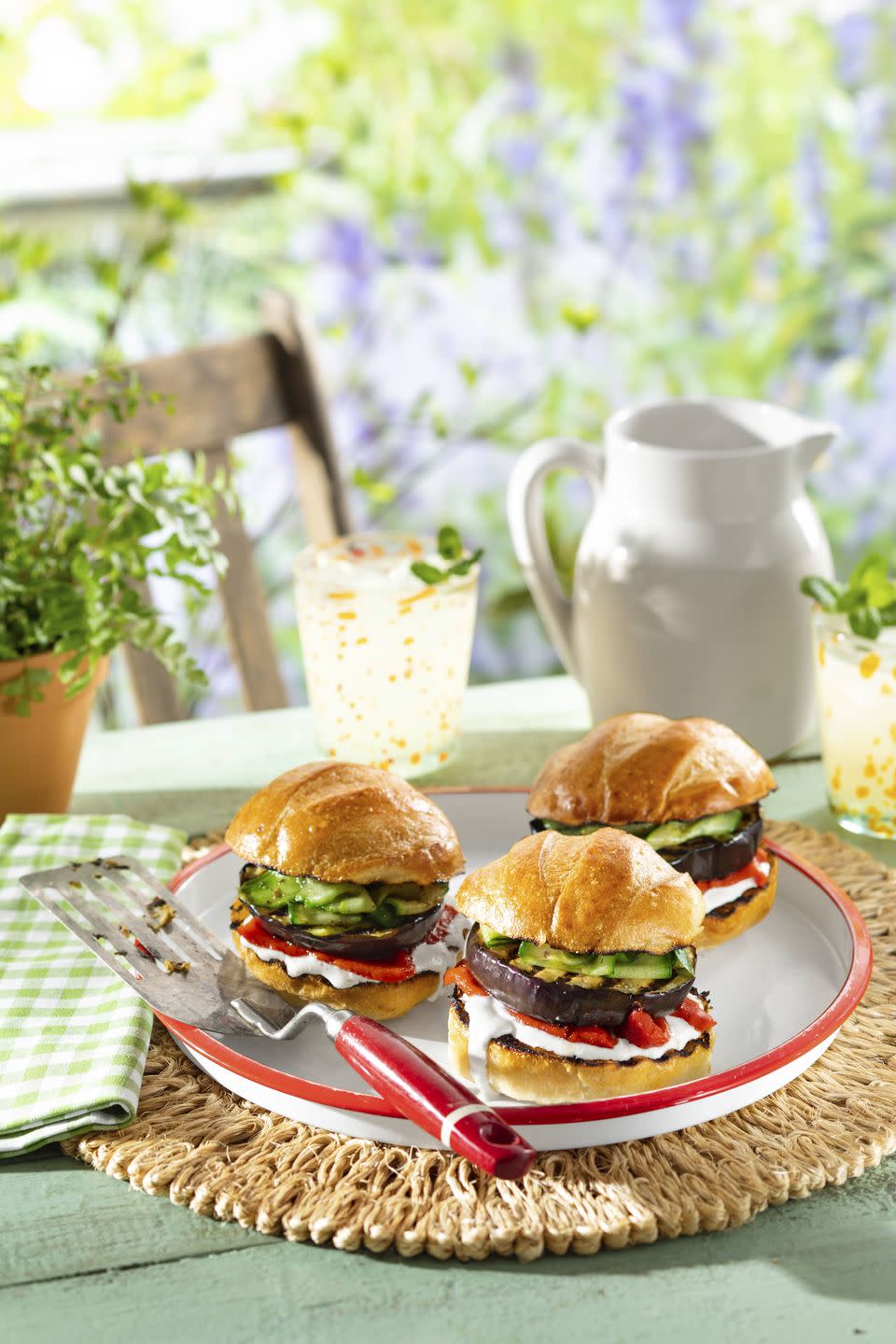 eggplant burgers with yogurt feta sauce and quick pickled cucumbers on a white serving plate with a spatula