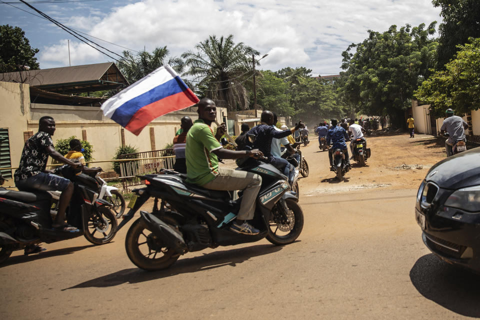 FILE - Supporters of Capt. Ibrahim Traore parade wave a Russian flag in the streets of Ouagadougou, Burkina Faso, Oct. 2, 2022. Ghana's President Nana Akufo-Addo, during his visit to the United States where he's attending the U.S.-Africa summit, claimed Burkina Faso had allegedly made an agreement with Russia's shadowy mercenary outfit the Wagner Group to bolster the country's security amid surging jihadi violence, in exchange for a mine. (AP Photo/Sophie Garcia, File)