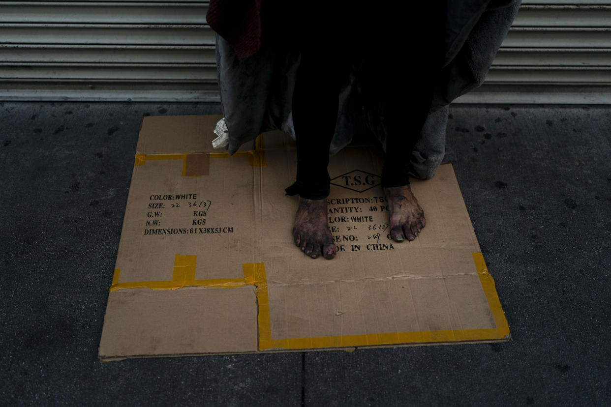 A mentally ill homeless man stands on a piece of cardboard on a sidewalk in Los Angeles, Friday, April 15, 2022. A controversial bill signed by Gov. Gavin Newsom could improve that by forcing people suffering from severe mental illness into treatment. But they need to be diagnosed with a certain disorder such as schizophrenia and addiction alone doesn't qualify. (AP Photo/Jae C. Hong)