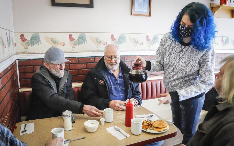 A waitress wearing a mask serves patrons.