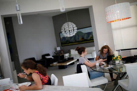 Daniela Menescal, who was injured by shrapnel during the mass shooting at Marjory Stoneman Douglas High School, does her homework next to her sisters at their house in Parkland, Florida, U.S., April 4, 2018. REUTERS/Carlos Garcia Rawlins/Files