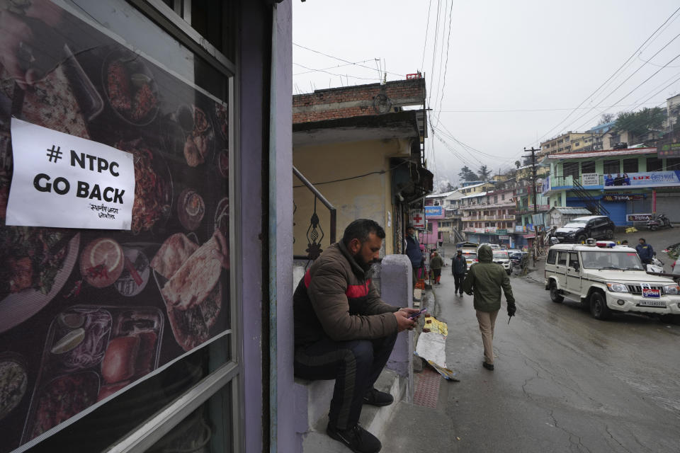 A poster calling for boycotting state owned hydro power project company is pasted on a shop, in Joshimath, in India's Himalayan mountain state of Uttarakhand, Jan. 20, 2023. For months, residents in Joshimath, a holy town burrowed high up in India's Himalayan mountains, have seen their homes slowly sink. They pleaded for help, but it never arrived. In January however, their town made national headlines. Big, deep cracks had emerged in over 860 homes, making them unlivable. (AP Photo/Rajesh Kumar Singh)