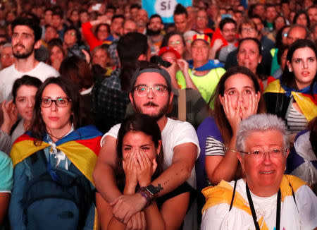 People react as they watch a session of the Catalonian regional parliament on a giant screen at a pro-independence rally in Barcelona, Spain, October 10, 2017. REUTERS/Gonzalo Fuentes