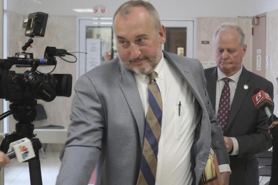 Attorney Tom Lemon, left, leads his client, former Kansas Senate Majority Leader Gene Suellentrop, right, through a crowd of reporters after a court hearing in which Suellentrop pleaded no contest to charges of driving under the influence and reckless driving, Monday, Oct. 25, 2021, in Topeka, Kan. The charges stem from an incident in March in which prosecutors say Suellentrop was speeding the wrong way down interstate highways in Topeka. (AP Photo/John Hanna)