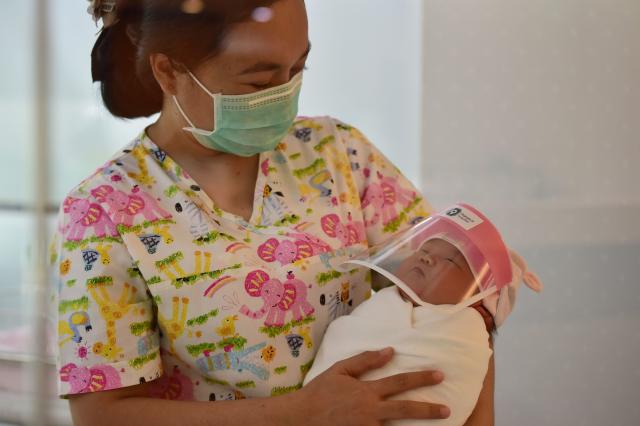 Newborn baby wears a face shield in Bangkok hospital