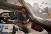 Scott See, 53, passes time in his tent at a homeless encampment set up along the boardwalk in the Venice neighborhood of Los Angeles, Tuesday, June 29, 2021. The proliferation of homeless encampments on Venice Beach has sparked an outcry from residents and created a political spat among Los Angeles leaders. (AP Photo/Jae C. Hong)