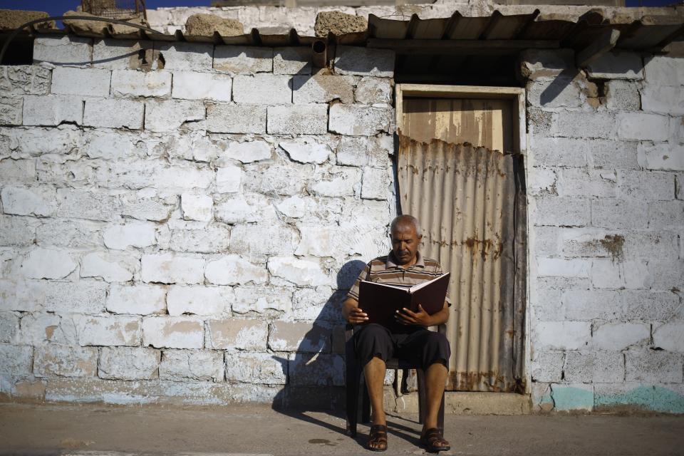 A Palestinian man reads a copy of the Koran outside his home at Al-Shati refugee camp in Gaza City on June 6.