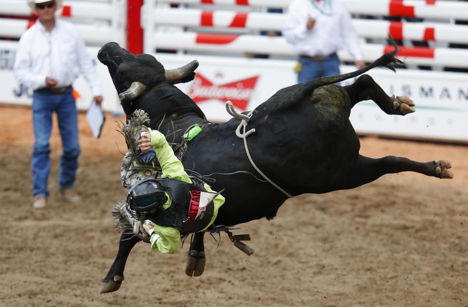 Buttar of Kindersley, Saskatchewan, slides off bull Burn It To The Ground in bull riding event during day 1 of the rodeo at the 102 Calgary Stampede in Calgary.