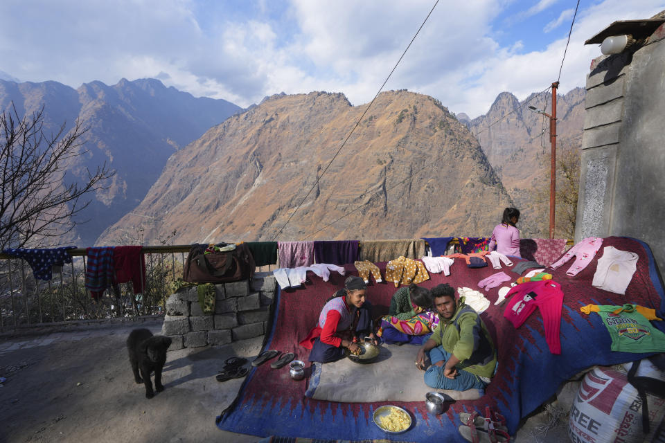 A family takes refuge outside their house in Joshimath, in India's Himalayan mountain state of Uttarakhand, Jan. 19, 2023. For months, residents in Joshimath, a holy town burrowed high up in India's Himalayan mountains, have seen their homes slowly sink. They pleaded for help, but it never arrived. In January however, their town made national headlines. Big, deep cracks had emerged in over 860 homes, making them unlivable. (AP Photo/Rajesh Kumar Singh)