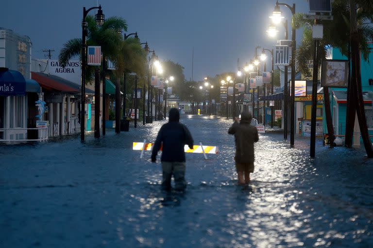 Periodistas avanzan en una inundación la zona céntrica después de que el Huracán Idalia pasara cerca de la costa el 30 de agosto de 2023 en Tarpon Springs, Florida.