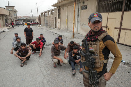 Displaced Iraqi men wait for a security check on a street as the battle between the Iraqi Counter Terrorism Service and Islamic State militants continues nearby, in western Mosul, Iraq, April 23, 2017. REUTERS/Marko Djurica