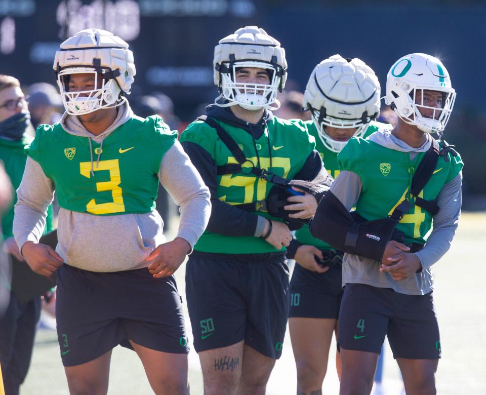 Oregon defensive players Brandon Dorlus, left, Popo Aumavae and Daymon David, right, work out with the team to begin the 2022 season.