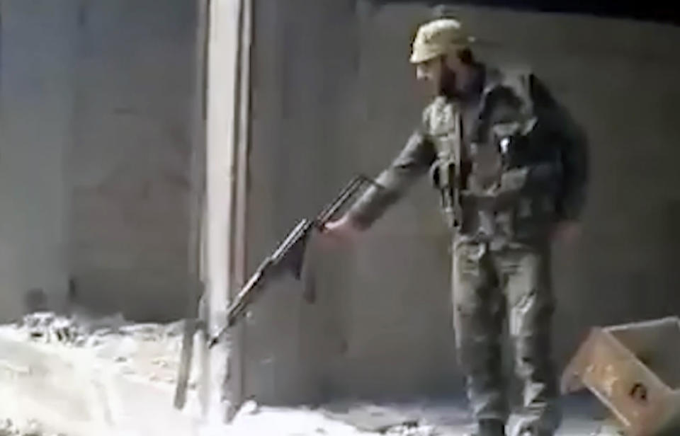 FILE - This frame grab from a 2013 video, shows a Syrian soldier firing into a large pit full of bodies, in the Tadamon neighborhood of Damascus, Syria. The U.S. State Department issued an entry ban into the United State Monday against a Syrian intelligence member who appeared in a video leaked last year showing him shooting people dead during the country's 12-year conflict. (AP Photo, File)