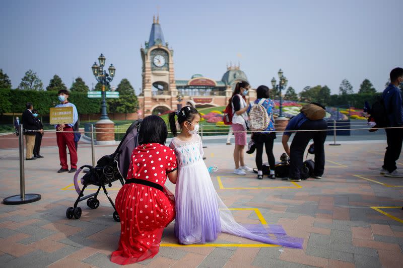 Visitors wearing face mask line up following social distancing markers at Shanghai Disney Resort as the Shanghai Disneyland theme park reopens following a shutdown due to the coronavirus disease (COVID-19) outbreak, in Shanghai