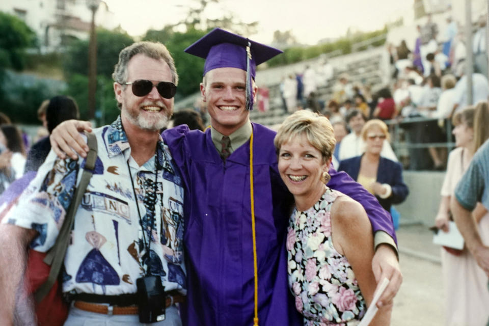 In this June 1993 photo provided by Kathleen McIlvain, Charles McIlvain, center, and his parents, Clark McIlvain, left, and Kathleen McIlvain, pose after Charles graduated from Taft High School in Woodland Hills, Calif. Charles McIlvain was one of 34 people killed when the dive boat Conception caught fire and sank off the coast of California on Sept. 2, 2019. (Kathleen McIlvain via AP)