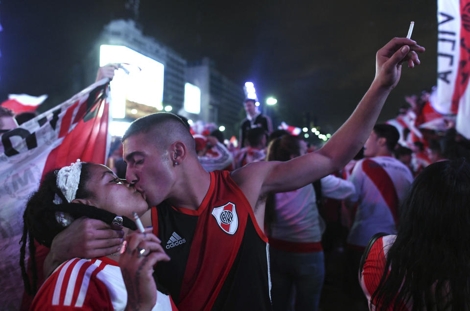 River Plate soccer fans kiss as they celebrate their team's 3-1 victory over Boca Juniors and clenching the Copa Libertadores championship title, at the Obelisk in Buenos Aires, Argentina, Sunday, Dec. 9, 2018. The South American decider was transferred from Buenos Aires to Madrid, Spain after River fans attacked Boca's bus on Nov. 10 ahead of the second leg. (AP Photo/Gustavo Garello)