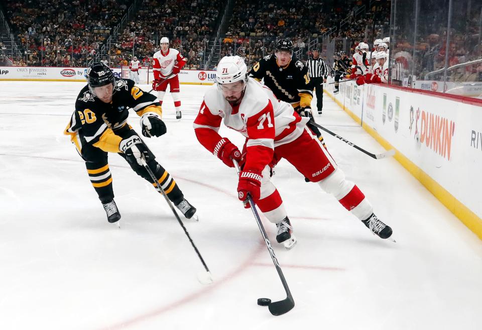 Red Wings center Dylan Larkin skates with the puck as Penguins center Lars Eller chases during the second period on Thursday, April 11, 2024, in Pittsburgh.