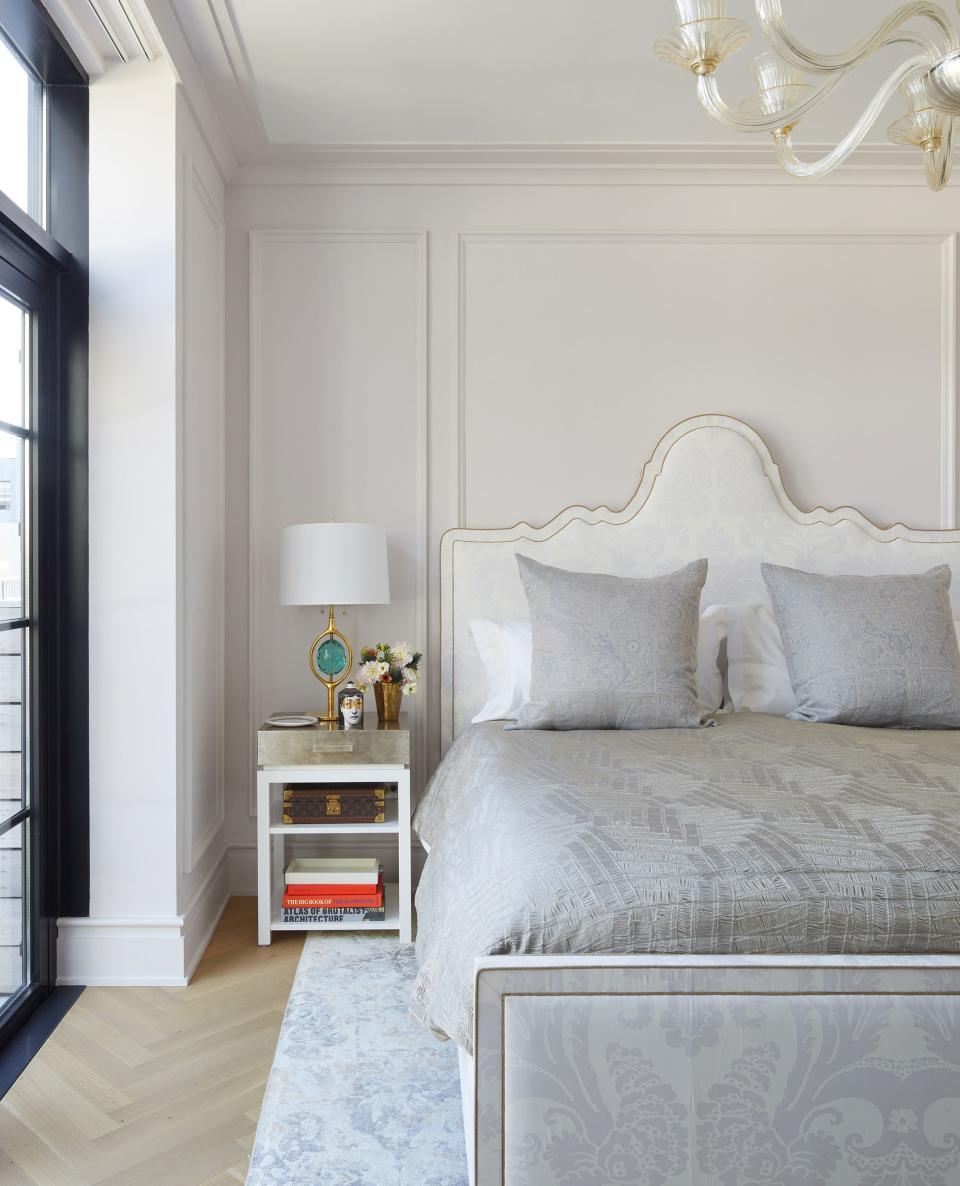 In the master bedroom, a Venetian glass chandelier from Fortuny hangs above a custom bed upholstered in Fortuny fabric. The table lamp is by Phoenix Gallery.