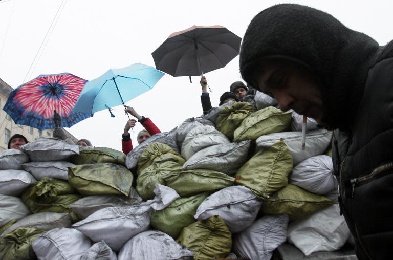 People carry umbrellas as they visit barricades of the opposition in Kiev on February 9, 2014