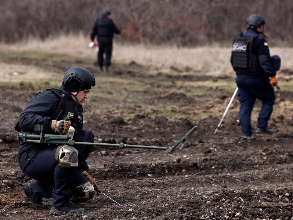 The Ukrainian Emergency Services surveying an area of farmland and electric power lines for land mines.