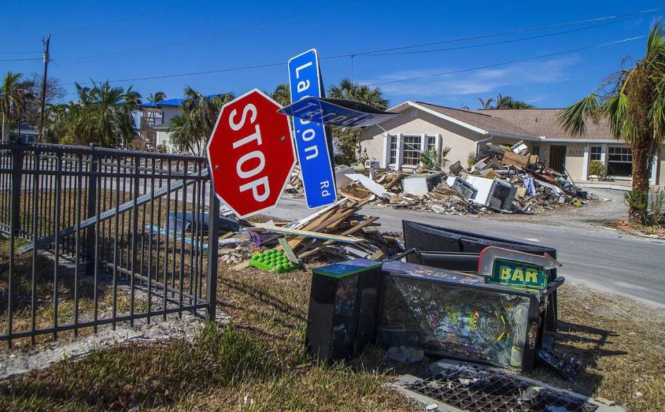 Una señal de alto derribada descansando sobre una valla en la esquina de las carreteras Lagoon y Tarpon en Fort Myers Beach, junto a objetos como una máquina de pinball y electrodomésticos, el miércoles 26 de octubre de 2022. Los objetos se encontraban entre las toneladas de escombros dejados luego del paso del huracán Ian, que golpeó la zona como una tormenta de categoría cuatro un mes antes.