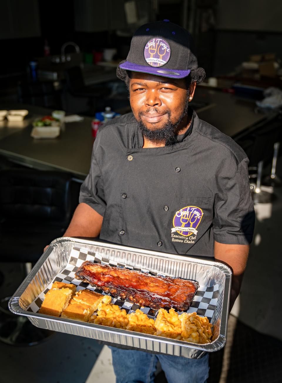 Romeo Diahn holds a platter of pork ribs, corn bread, and macaroni and cheese at Kitchen Spaces in the Drake neighborhood, where he is hosting his Thursday-only restaurant, Chef Tony's Culinary Delights.