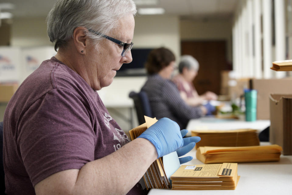 In this April 14, 2020 photo, Pam Fleming and fellow workers stuff ballots and instructions into mail-in envelopes at the Lancaster County Election Committee offices in Lincoln, Neb. Officials in Nebraska are forging ahead with plans for the state’s May 12 primary despite calls from Democrats to only offer voting by mail and concerns from public health officials that in-person voting will help the coronavirus spread. Republican leaders have encouraged people to request absentee ballots but say polling places will be open. (AP Photo/Nati Harnik)