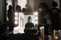 An hairdresser is reflected in a mirror as she waits in the backstage at the "We are Made in Italy - Black Lives Matter in Italian fashion Collection" event during the Milan's fashion week in Milan, Italy, Thursday, Sept. 17, 2020. (AP Photo/Antonio Calanni)