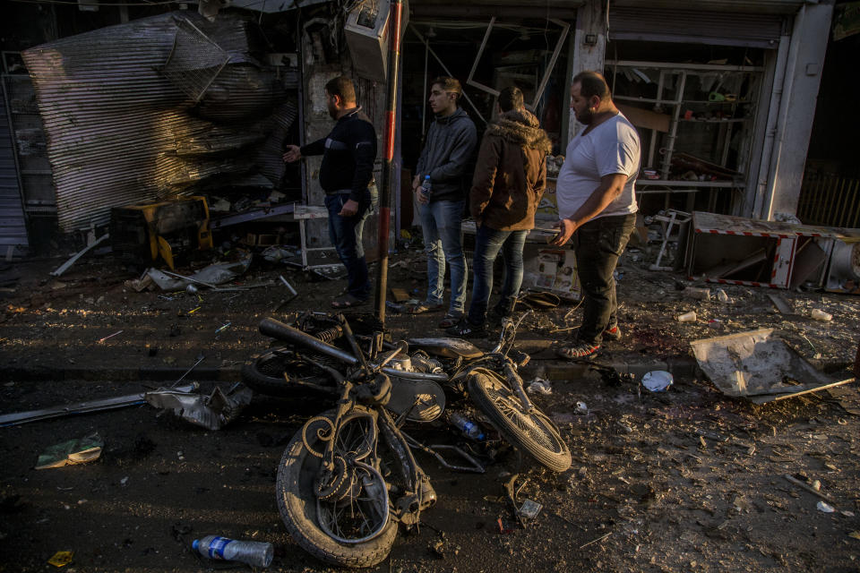 People check the aftermath of a car bomb blast in the city of Qamishli, northern Syria, Monday, Nov. 11, 2019. Three car bombs went off Monday in then city killing several and wounding tens of people. (AP Photo/Baderkhan Ahmad)
