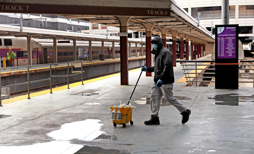 BOSTON, MA - APRIL 13: A custodian walks past empty train platforms at South Station in Boston during the COVID-19 pandemic on April 14, 2020. (Photo by David L. Ryan/The Boston Globe via Getty Images)