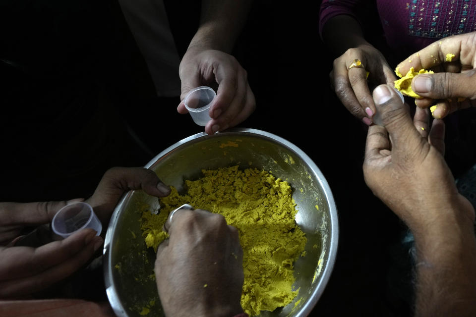 Patients hold small containers to be filled with a herbal paste to take home after receiving a fish therapy for asthma, in Hyderabad, India, Saturday, June 8, 2024. Every year thousands of asthma patients arrive here to receive this fish therapy from the Bathini Goud family, which keeps a secret formula of herbs, handed down by generations only to family members. The herbs are inserted in the mouth of a live sardine, or murrel fish, and slipped into the patient's throat. (AP Photo/Mahesh Kumar A.)