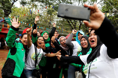 Women Gojek drivers react as they take pictures during Go-Food festival in Jakarta, Indonesia, October 27, 2018. Picture taken October 27, 2018. REUTERS/Beawiharta