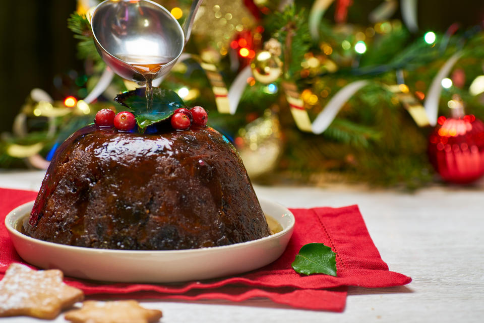 Burning Christmas pudding on decorated fir tree background. (Getty Images)