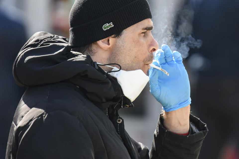 A man in a protective mask and gloves as a preventive measure against COVID-19 smokes on street in Kyiv, Ukraine. Source: Getty