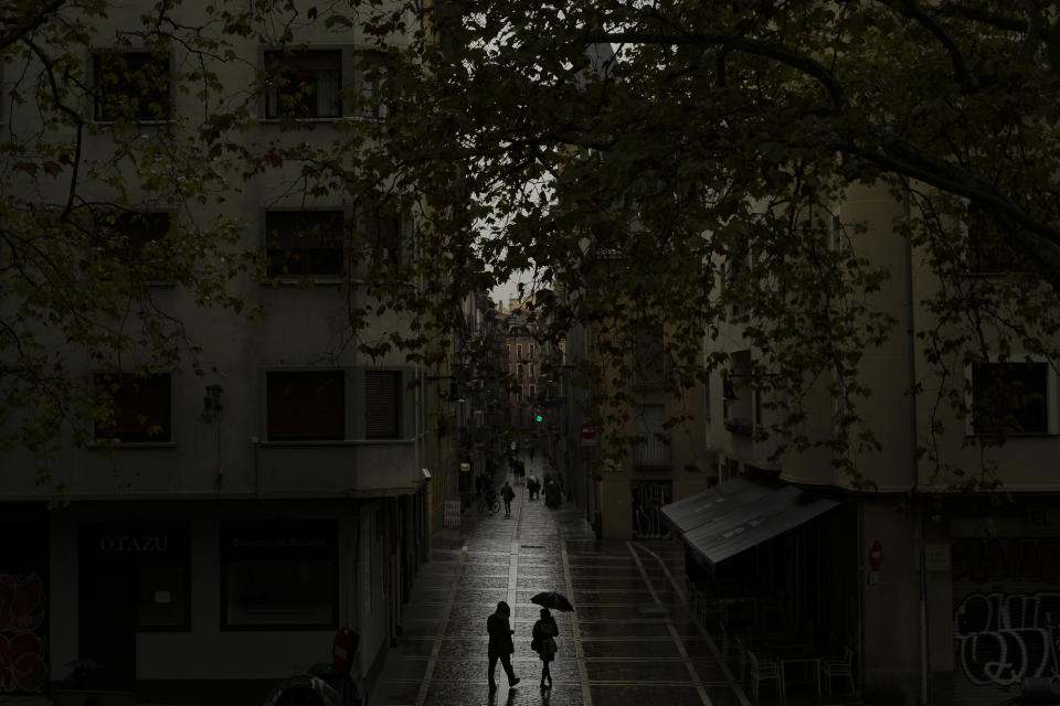 Pedestrian shelters from the rain under an umbrella while walking along the old city during a raining autumn day, in Pamplona, northern Spain, Saturday, Oct. 3, 2020. (AP Photo/Alvaro Barrientos)