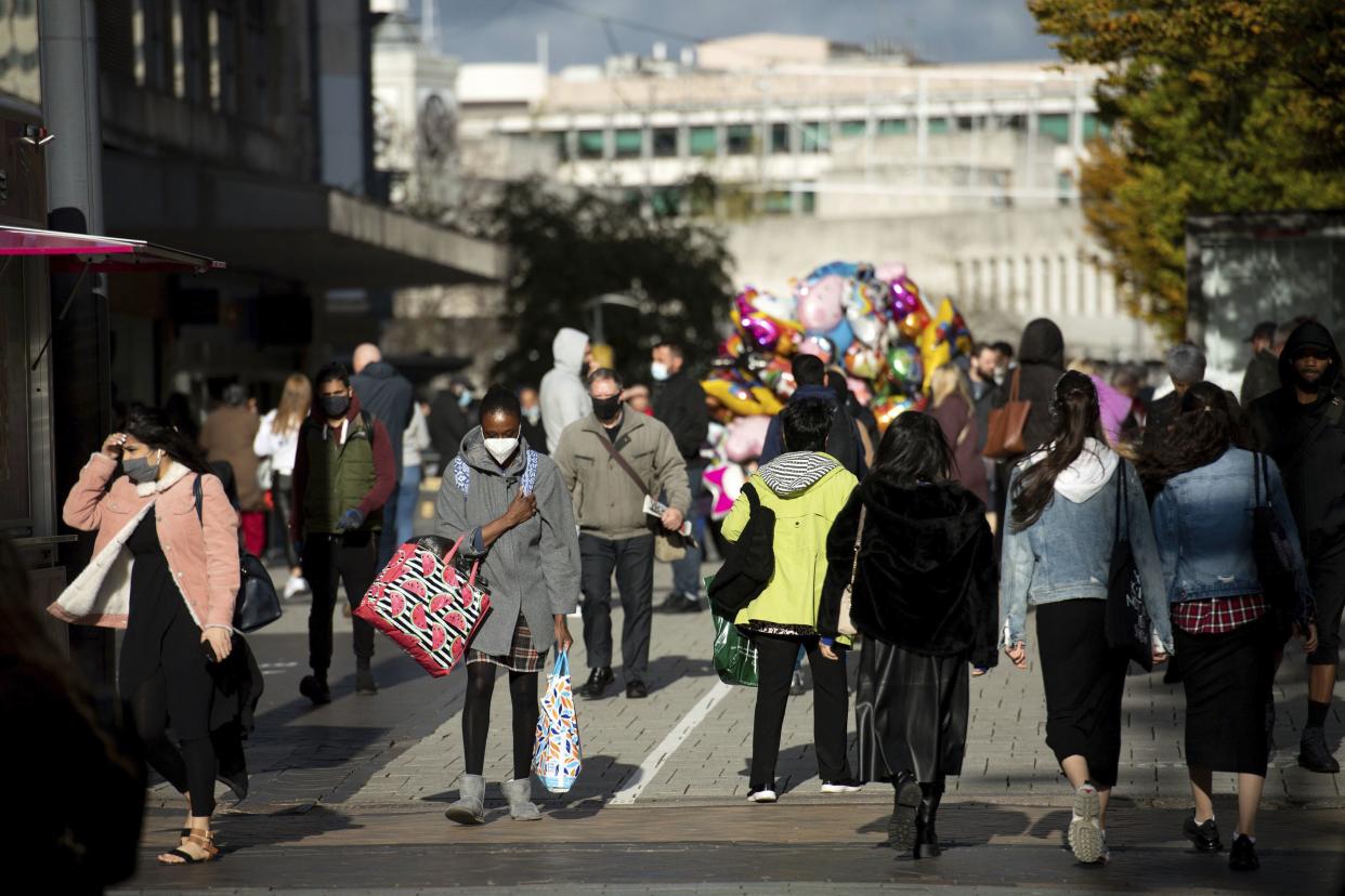 People walk through Birmingham, England on Monday, Nov. 2, 2020, ahead of England heading toward a tougher lockdown starting Thursday, with nonessential shops and hairdressers closing for a month and people allowed to leave home for only a short list of reasons, including exercise.