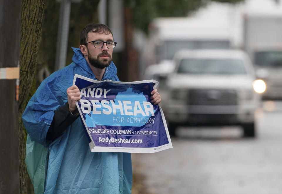 Joe Newberg, of Louisville, holds an Andy Beshear campaign sign while standing along Frankfort Ave. in Louisville, Ky., Tuesday, Nov. 5, 2019. (AP Photo/Bryan Woolston)