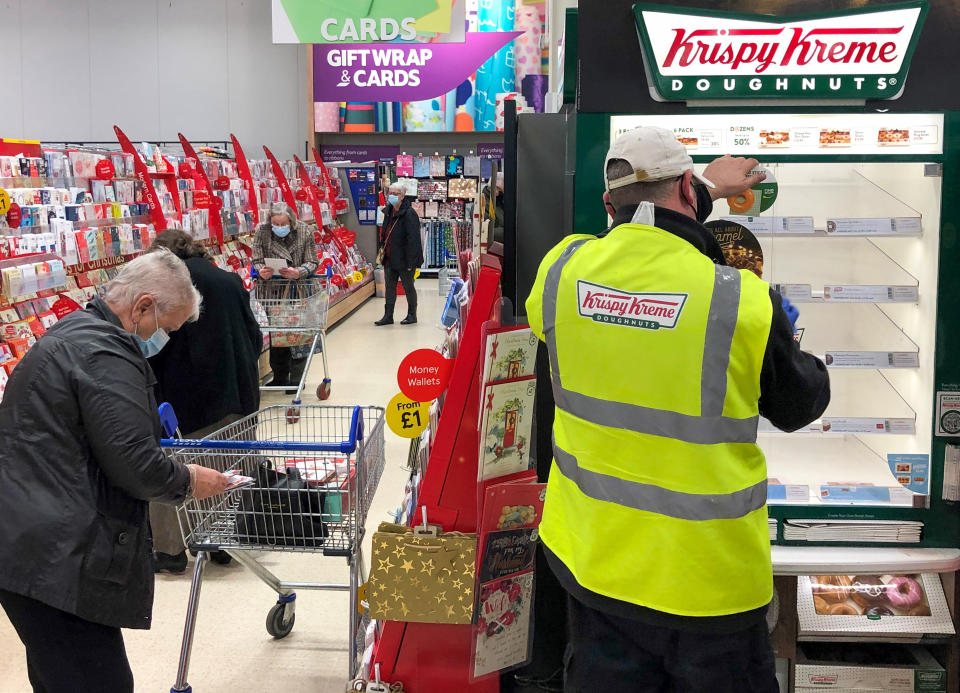 A photo of a Krispy Kreme fridge being filled as shoppers complete their grocery shop.