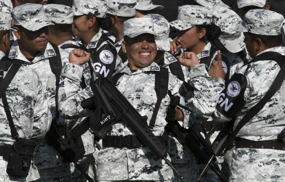 FILE - A National Guardsman smiles while stretching before the start of a presentation ceremony at a military field in Mexico City, June 30, 2019. The National Guard which includes federal police, marines, soldiers and new recruits was created to stem endemic violence and restore peace in the country. (AP Photo/Christian Palma, File)