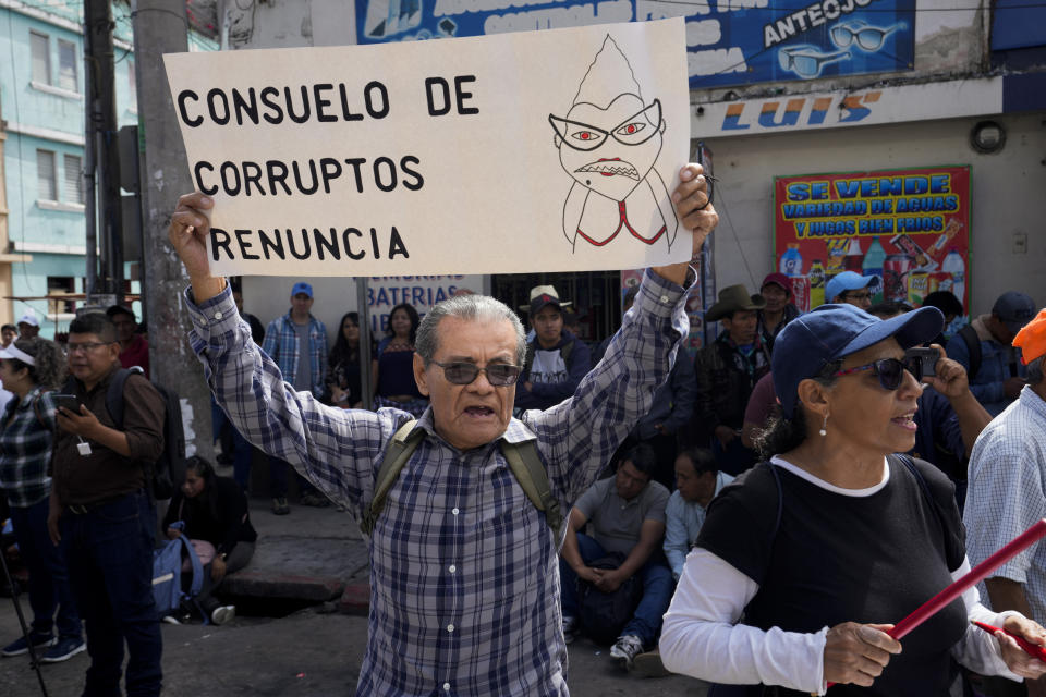 Protestors demand the resignation of Attorney General Consuelo Porras and prosecutor Rafael Curruchiche in Guatemala City, Monday, Oct. 2, 2023. The sign uses a play on words, with "Consuelo" meaning "help,' in Spanish : "Consuelo is help for the corrupt. Resign." Indigenous organizations are blocking some roads across the country to protest the attorney general's latest raids on Guatemala’s top electoral tribunal after elections. (AP Photo/Moises Castillo)