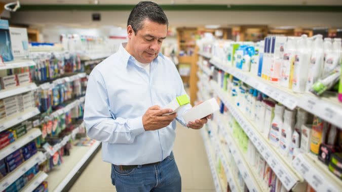 Man shopping at the pharmacy and comparing two medical products - healthcare and medicine concepts.