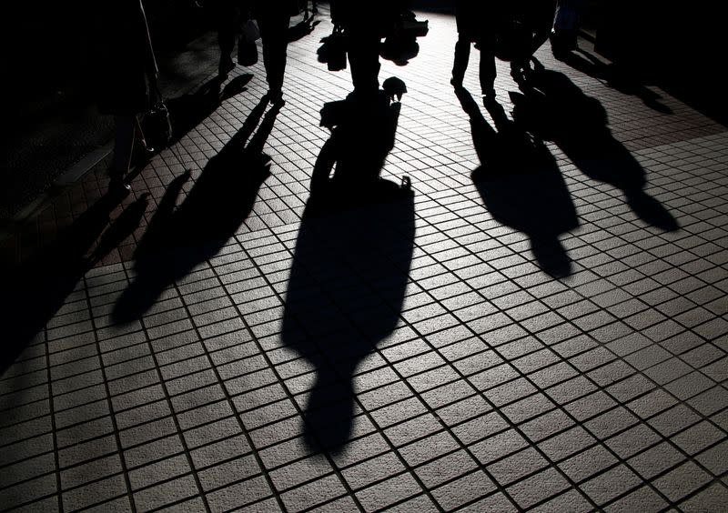 Pedestrians cast shadows as they make their way at a financial district in Tokyo