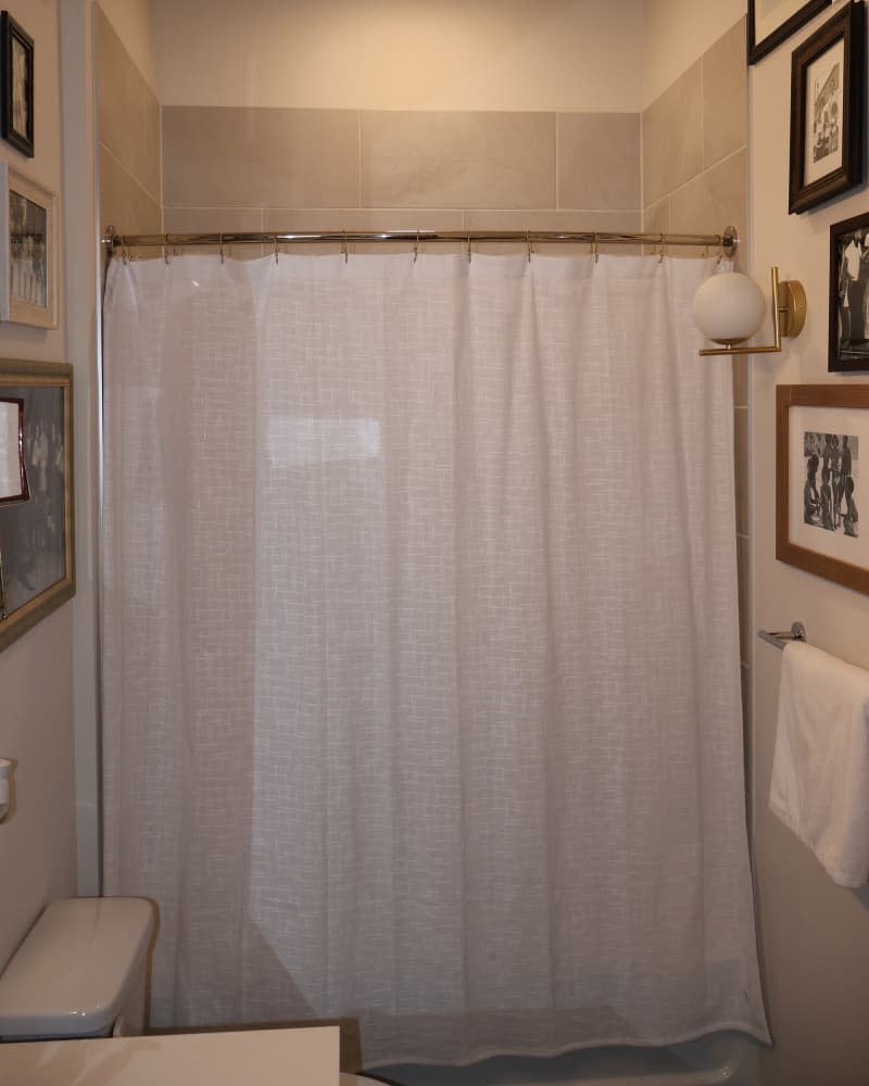 Beige and white bathroom with single white shower curtain before makeover