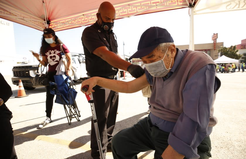 LOS ANGELES, CA - FEBRUARY 24: She Tang Tan, 80, receives the Pfizer COVID-19 vaccine from LA City Fire Captain Paramedic Leon Dunn as the LA City CORE mobile team is staging a vaccination clinic in Chinatown for senior citizens, in an attempt to improve access to the vaccine among vulnerable populations. Chinatown on Wednesday, Feb. 24, 2021 in Los Angeles, CA. (Al Seib / Los Angeles Times).