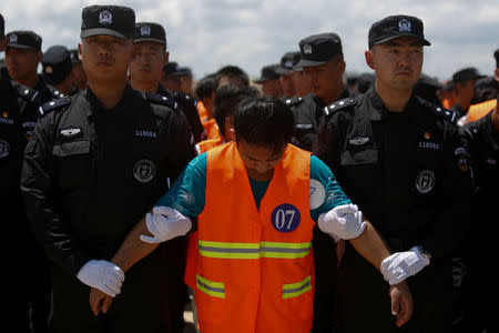 Chinese nationals (in orange vests) who were arrested over a suspected internet scam, are escorted by Chinese police officers before they were deported at Phnom Penh International Airport, in Phnom Penh, Cambodia, October 12, 2017. REUTERS/Samrang Pring