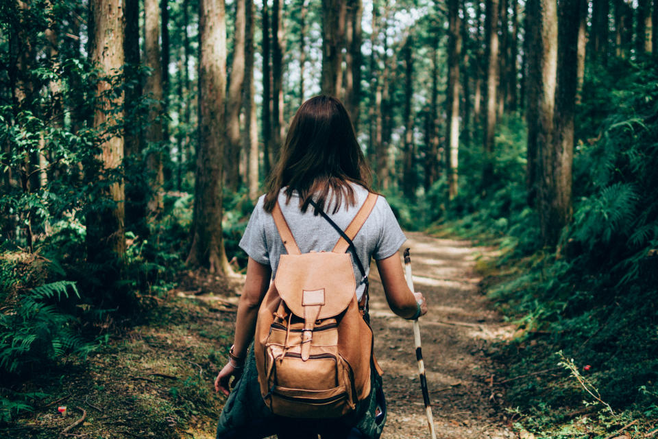 Woman hiking through forest with backpack on